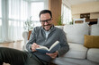 © Migma_Agency - Happy man enjoying reading a book at home