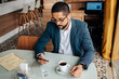 © kleberpicui - Business man using smartphone in cafe. Concepts of remote work, freelance lifestyle, business routine, technology, urban life and modern professional