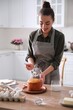 © New Africa - Young woman decorating traditional Easter cake with glaze in kitchen