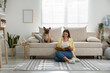 © New Africa - Woman with her cute dog and magazine relaxing near sofa at home