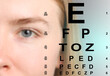 © New Africa - Vision check during visiting ophthalmologist. Eye chart and woman on color background