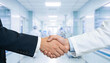 © Art_spiral - Closeup handshake between doctor in lab coat and business partner in modern hospital corridor healthcare collaboration agreement medical service partnership concept