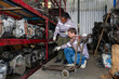 © offsuperphoto - Workers working in a auto parts warehouse, examining salvaged parts. The warehouse is well-organized with multiple shelves