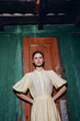 © SHOTPRIME STUDIO - woman dress fashion pose doorway vintage yellow wall stands confidently in front of a weathered door with a green backdrop creating a striking fashion portrait