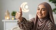 © Hamid - Smiling Muslim woman wearing hijab giving a thumbs up gesture.