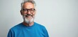 © Vadym - Mature smiling man with beard and glasses looks at camera against light background. He wears blue sweatshirt and shows confidence and joy in his expression, representing wisdom and happiness.