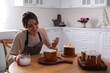 © New Africa - Young woman decorating traditional Easter cake with glaze in kitchen. Space for text