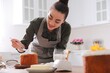 © New Africa - Young woman decorating traditional Easter cake with glaze in kitchen. Space for text