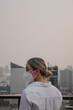 © blackday - Woman wearing protective face mask standing on rooftop with modern city skyline