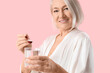 © Pixel-Shot - Mature woman taking collagen powder on pink background