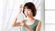 © Trickster* - 自然光の中でヘアスタイルを確認する若い女性, Young woman checking her hairstyle in natural light