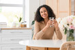 © Pixel-Shot - Young African-American woman with glass of water at table in kitchen