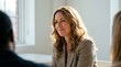 © ryker - Smiling professional woman in light office setting converses with colleagues, warm natural light highlights her wavy hair and blazer conveying friendly confidence