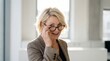 © ryker - Confident professional woman in blazer smiling and adjusting eyeglasses in bright modern office, approachable expression and natural lighting
