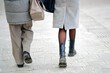 © Tricky Shark - Back view of couple walking together along paved city sidewalk in winter coats and boots, everyday urban lifestyle, calm street mood, casual fashion during cold season. Urban fashion. Selective focus