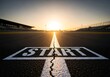 © Faheem - Low angle view of the word START painted on the professional motorsport racing circuit asphalt, representing new beginnings and success, illuminated by a brilliant sunrise flare
