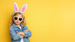 © Nataliia Pyzhova - Cute little girl in bunny ears and heart-shaped sunglasses posing with arms crossed on yellow background. Fun Easter fashion concept.