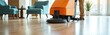 © Viktor - Man uses automated scrubber machine to clean hotel lobby floor. Worker maintains polished hardwood surface near blue armchairs and green plant, ensuring guest comfort and hygiene.