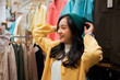 © Parichat - Young woman happily trying on beanie in clothing store