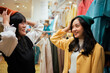 © Parichat - Young Asian women trying on beanies in clothing store