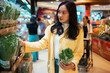 © Parichat - Young woman shopping for fresh herbs in supermarket