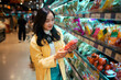© Parichat - Woman choosing fresh tomatoes in grocery store produce aisle