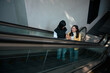 © Parichat - Asian young women friends riding escalator shopping mall