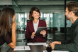 © Stock 4 You - Smiling gesturing female corporate boss manager holding tablet, presents project to collaborative colleagues or client. Business mature CEO businesswoman leader leads diverse team meeting in office.