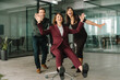 © Stock 4 You - Happy colleagues celebrate success at work. Smiling two young coworkers push woman boss CEO in chair in business office workspace. Full body. Teamwork, victory and fun corporate culture environment.