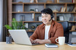 © Liubomir - Asian man working from home office, typing on a laptop and wearing a headset, engaging in a video call or online meeting, creating a productive and focused work environment