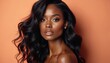 © Maryna - Beautiful black woman with voluminous wavy hair and perfect makeup. She poses confidently against an orange backdrop. Her style is elegant and sophisticated, ideal for beauty ads.