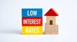 © Shakib - Low interest rates text on stacked blocks next to small wooden house