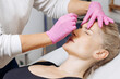 © wedmoments.stock - Female patient receiving Botox injection procedure by a medical professional wearing pink gloves in a clinical setting with medical equipment visible in the background