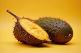 Whole and cut salak fruit shown on yellow background. Spiky brown peel reveals juicy yellow flesh. Exotic snake fruit is ripe and ready to eat. Healthy snack from asia.