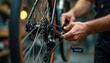© Viktor - Man works on bicycle gears. Mechanic uses tool to fix bike chain and wheel in repair shop. Technician performs bike maintenance in workshop. Close up of hands working.