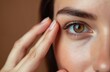 © Viktor - Young woman examines fine lines near her eye. She gently touches skin, checking for wrinkles and signs of aging. Focused on facial care and skin health.