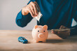© sorapop - Man puts money in piggy bank for car, gdp, savings, insurance, health, finance, budget and save goals while holding cash for personal investment and global economic growth trends