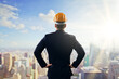 © Who is Danny - Businessman in suit and construction helmet looking at city skyline with hands on hips, symbolizing vision, planning and future development.