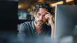 © Lumi Stock Studio - A worried male professional sitting at his desk, leaning his head on his hand while looking at a computer screen, depicting deep thought, stress, or a difficult business decision