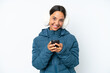 © luismolinero - Young hispanic woman wearing a winter earmuffs isolated on white background sending a message with the mobile