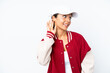 © luismolinero - Young hispanic woman wearing a baseball uniform isolated on white background listening to something by putting hand on the ear
