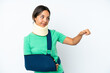 © luismolinero - Young hispanic woman wearing a neck brace and sling isolated on white background giving a thumbs up gesture