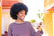 © luismolinero - African American girl using mobile phone at outdoors with happy expression