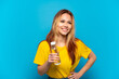 © luismolinero - Teenager girl with a bottle of water over isolated blue background posing with arms at hip and smiling