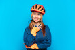 © luismolinero - Young cyclist girl isolated on blue background looking up while smiling