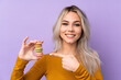 © luismolinero - Teenager girl over isolated purple background holding colorful French macarons and pointing it