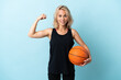 © luismolinero - Young Russian woman playing basketball isolated on blue background doing strong gesture