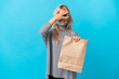 © luismolinero - Young Russian woman holding a grocery shopping bag isolated on blue background covering eyes by hands and smiling