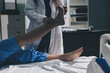 © Ketnapa - Doctor examining and supporting injured ankle of female patient in hospital room, providing medical assistance and treatment for sprain or fracture
