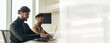 © Prostock-studio - Two men sit at a desk in a bright office space focused on their laptops. They work silently while enjoying a productive day at the workplace.